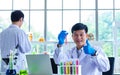 Portrait shot of Asian professional mature male scientist in white lab coat and rubber gloves sitting look at camera smiling