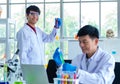 Portrait shot of Asian professional mature male scientist in white lab coat and rubber gloves sitting look at camera smiling