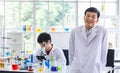 Portrait shot of Asian professional successful mature male scientist in white lab coat rubber gloves standing crossed arms smiling Royalty Free Stock Photo