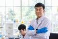 Portrait shot of Asian professional successful mature male scientist in white lab coat rubber gloves standing crossed arms smiling Royalty Free Stock Photo