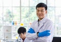 Portrait shot of Asian professional successful mature male scientist in white lab coat rubber gloves standing crossed arms smiling Royalty Free Stock Photo