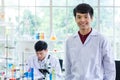 Portrait shot of Asian professional successful young handsome male scientist in white lab coat rubber gloves standing crossed arms Royalty Free Stock Photo