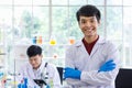 Portrait shot of Asian professional successful young handsome male scientist in white lab coat rubber gloves standing crossed arms Royalty Free Stock Photo