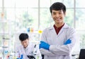 Portrait shot of Asian professional successful young handsome male scientist in white lab coat rubber gloves standing crossed arms Royalty Free Stock Photo