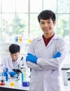 Portrait shot of Asian professional successful young handsome male scientist in white lab coat rubber gloves standing crossed arms Royalty Free Stock Photo