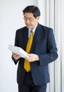 Portrait shot of Asian senior old successful wise businessman in formal suit with brown necktie and golden eyeglasses standing