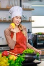 Portrait shot of Asian young beautiful female chef housewife wears white tall cook hat and apron standing smiling posing with Royalty Free Stock Photo