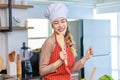 Portrait shot of Asian young beautiful female chef housewife wears white tall cook hat and apron standing smiling posing with Royalty Free Stock Photo