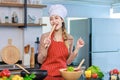 Portrait shot of Asian young beautiful female chef housewife wears white tall cook hat and apron standing smiling posing with Royalty Free Stock Photo