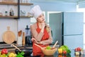 Portrait shot of Asian young beautiful female chef housewife wears white tall cook hat and apron standing smiling posing thinking Royalty Free Stock Photo