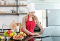 Portrait shot of Asian young cute female chef wears white tall cook hat and apron smiling posing look at camera learning cooking