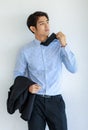 Portrait shot of Asian young happy successful businessman take black formal jacket uniform off hold it on hand and catch neck tie Royalty Free Stock Photo