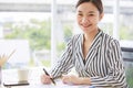 Portrait shot of Asian young pretty successful friendly female businesswoman wears black and white stripe suit sit smile work with Royalty Free Stock Photo