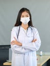 Portrait shot of Asian young professional successful female doctor practitioner wearing white lab coat and face mask with Royalty Free Stock Photo