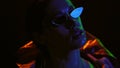 Portrait shot of a beautiful girl wearing down jacket and sunglasses in neon color lights . Pretty girl in neon light on Royalty Free Stock Photo