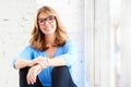 Happy mature woman looking at camera and smiling while relaxing at the window Royalty Free Stock Photo