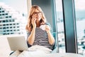 Happy mature woman drinking morning coffee and giving a call while working from home Royalty Free Stock Photo