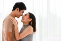 Portrait shot of cute smiling young Asian lover couple standing and passionate kissing together in the bedroom at weekends.