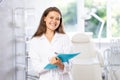 Portrait shot of doctor holding clipboard in hand while standing in medical esthetic office