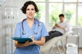 Portrait shot of female doctor holding clipboard in hand while standing in medical esthetic clinic
