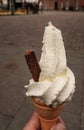 Portrait shot of a hand held whipped ice cream with a chocolate flake sticking out the side,  against a plain Royalty Free Stock Photo