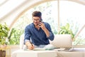 Casual businessman sitting on the couch at home while making a call and taking notes on notepad Royalty Free Stock Photo