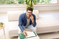 Casual businessman sitting on the couch at home while making a call and taking notes on notepad Royalty Free Stock Photo