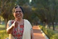 Portrait shot of a happy looking senior north Indian woman wearing traditional chikan kari Indian salwar kameez showing a thumbs