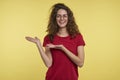 A portrait shot of happy smiling brunette female, showing palms to blank copy space, isalated over yellow background Royalty Free Stock Photo
