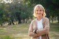 Portrait shot of happy, successful, relax caucasian senior woman smiling with a carefree look toward the camera at the park as a