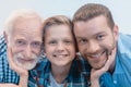 Portrait shot of little boy, grandfather and father smiling and looking Royalty Free Stock Photo