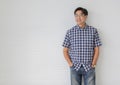 Portrait shot of middle aged asian male model with short black hair wearing blue plaid shirt with stand smiling in front of white Royalty Free Stock Photo