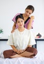 Portrait shot of Millennial Asian female relaxed customer sitting on massage bed while professional Thai masseuse aromatherapy