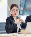 Portrait shot of Millennial Asian young professional successful female businesswoman in formal suit with eyeglasses sitting Royalty Free Stock Photo