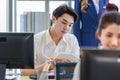 Portrait shot of Millennial Asian young professional successful male businessman sitting smiling looking at camera working typing Royalty Free Stock Photo