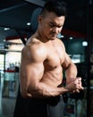 Portrait shot of shirtless adult Asian men show off his strong bicep and arm muscle inside of fitness gym. Bodybuilding or Royalty Free Stock Photo