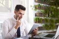 Careworn businessman working on digital tablet while sitting at office desk Royalty Free Stock Photo