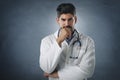 Portrait shot of thinking male doctor standing at isolated background Royalty Free Stock Photo