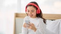 Portrait shot of a young adult Asian woman in casual white clothes using a digital smartphone to search for the popular music Royalty Free Stock Photo