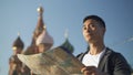 Portrait shot of a young Asian man looking at map. The Cathedral of Vasily the Blessed on background, Moscow Russia. Red Royalty Free Stock Photo