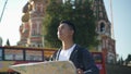 Portrait shot of a young Asian man looking at map. The Cathedral of Vasily the Blessed on background, Moscow Russia. Red