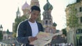 Portrait shot of a young Asian man looking at map. The Cathedral of Vasily the Blessed on background, Moscow Russia. Red