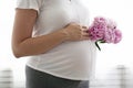 Portrait shot of young beautiful woman on third trimester of pregnancy. Close up of pregnant female with arms on her round belly.