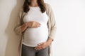 Portrait shot of young beautiful woman on third trimester of pregnancy. Close up of pregnant female with arms on her round belly.