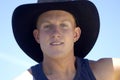 A portrait shot of a young blond male cowboy with only the sky as the background.