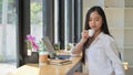 Young woman wearing a white dress holding a coffee to drink while resting from a laptop working in an office Royalty Free Stock Photo