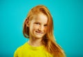 Portrait of shy child girl, expresses embarrassment, wears yellow t-shirt, has beautiful red hair and freckles, portrait