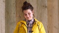 Portrait of shy, introverted woman showing a cheerful facial expression while isolated against a wooden background with