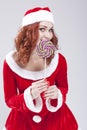 Portrait of Shy Sensual Smiling Santa Helper with Lollipop. Against white. Royalty Free Stock Photo