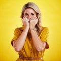 Portrait, shy and woman with fist on face in studio isolated on a yellow background. Female person, introvert and